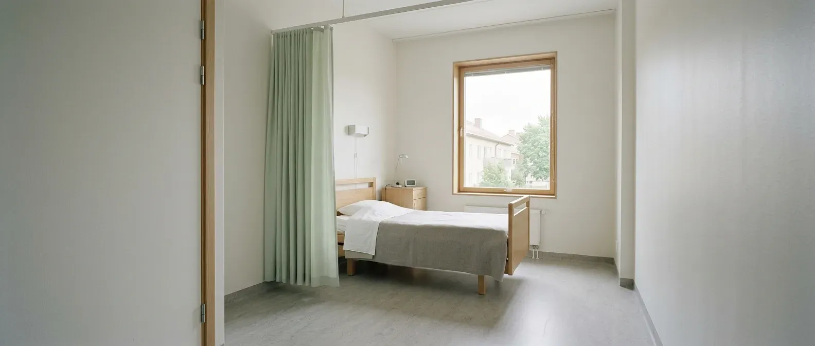 Vårdrum med ett ljusgrönt skärmdraperi vid sängen