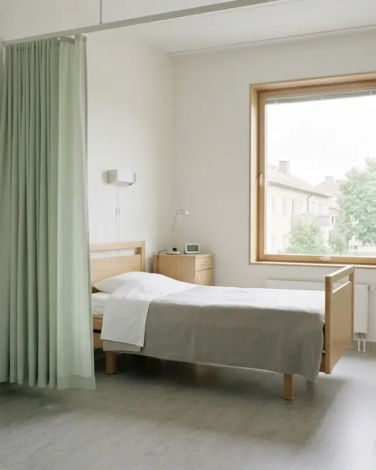 Vårdrum med ett ljusgrönt skärmdraperi vid sängen